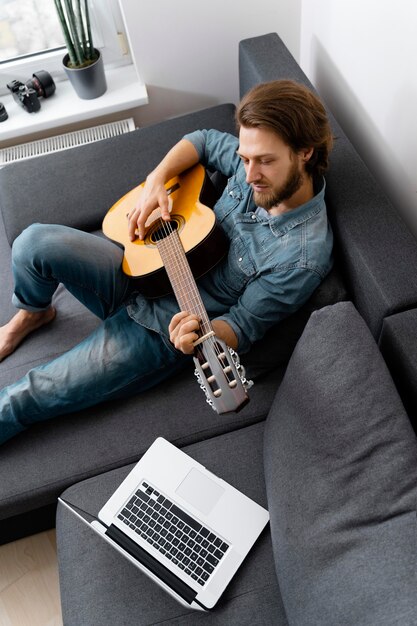 Mediums shot hombre tocando la guitarra en el sofá