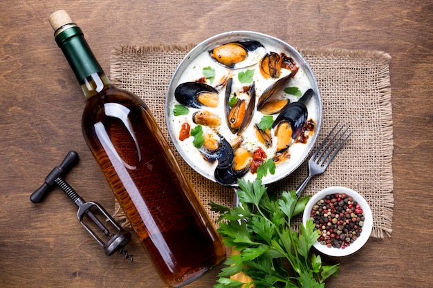 Foto gratuita mejillones planos en salsa blanca y botella de vino.