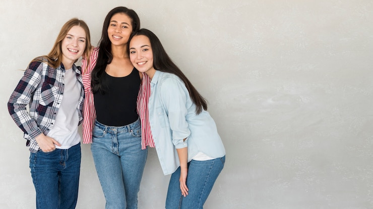 Foto gratuito mejores amigas en jeans y camisas posando en estudio.