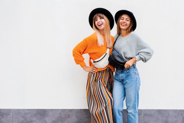 Foto gratuita mejores amigos abrazándose, un par de chicas elegantes posando en blanco