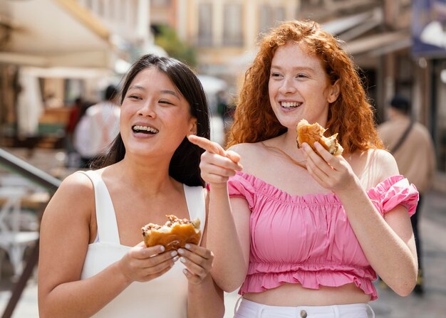 Mejores amigos comiendo juntos algo de comida callejera