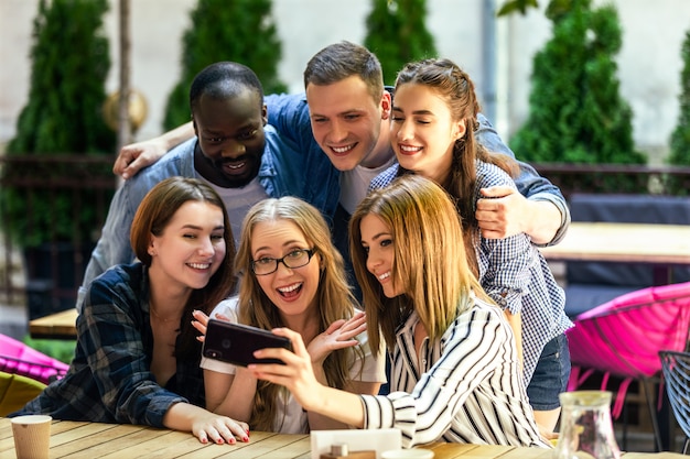 Los mejores amigos están tomando fotos autofotos en el teléfono inteligente en el acogedor restaurante