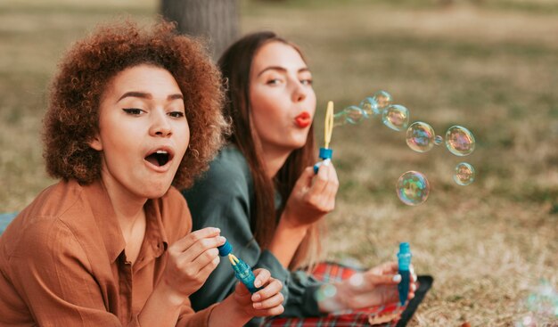 Mejores amigos haciendo pompas de jabón en otoño