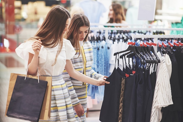 Los mejores amigos juntos pasan tiempo. Dos hermosas chicas hacen compras en la tienda de ropa. Se vestían con la misma ropa