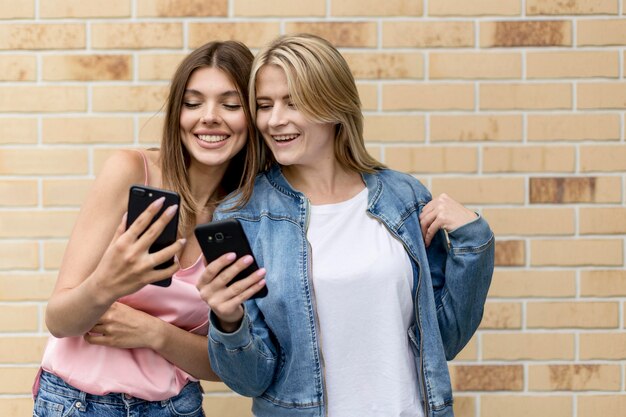 Mejores amigos mirando en sus teléfonos móviles