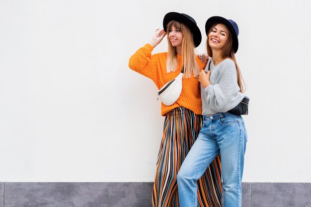 Mejores amigos, pareja de chicas elegantes posando en blanco