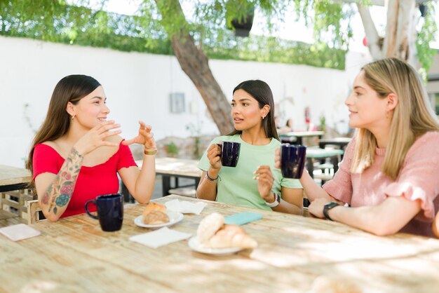 Mejores amigos poniéndose al día en un café. Diversas mujeres jóvenes bebiendo café y comiendo pasteles durante el brunch. Besties hablando y teniendo una buena conversación.