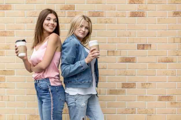 Mejores amigos posando con sus tazas de café con espacio de copia