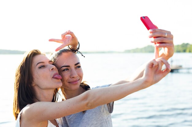 Los mejores amigos que se toman un selfie junto a un lago.