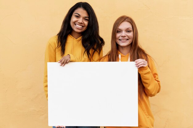 Mejores amigos sosteniendo una tarjeta en blanco