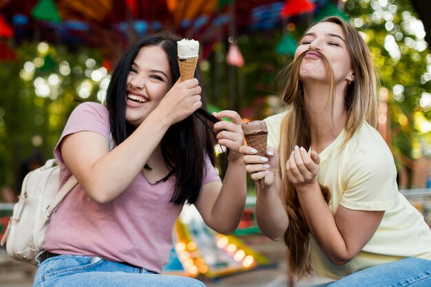 Mejores amigos de tiro medio disfrutando de un helado y posando de una manera divertida