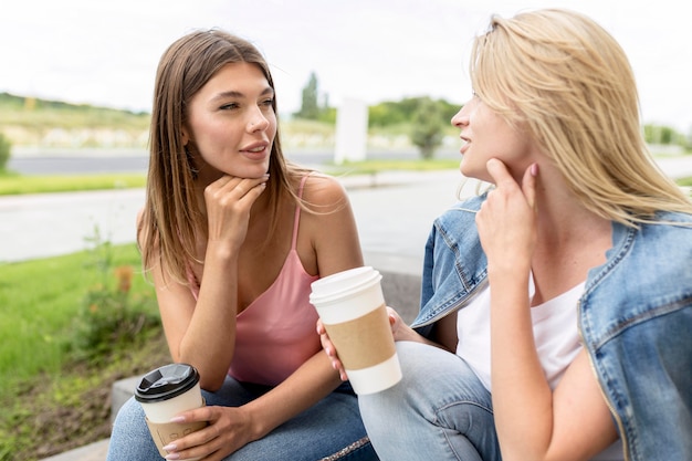 Mejores amigos de vista frontal sosteniendo unas tazas de café de papel