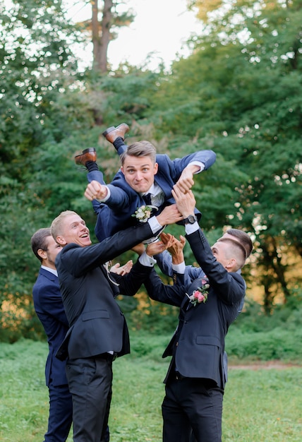 Los mejores hombres están vomitando novios al aire libre en el parque, divertido día de boda