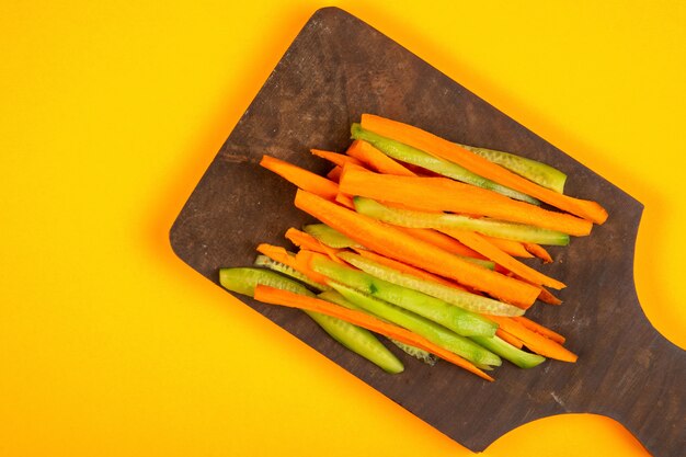 los mejores palitos de zanahoria y pepino en la tabla de cortar de madera en amarillo