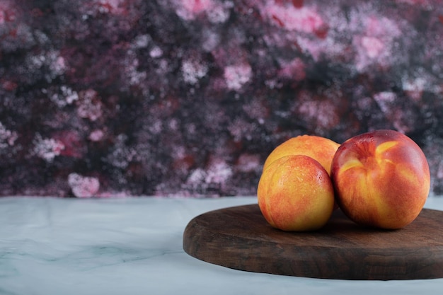 Foto gratuita melocotones rojos amarillos sobre tabla de madera.