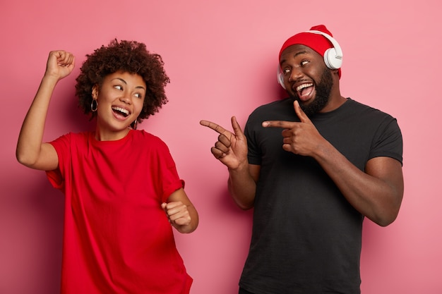 La melodía cambia el estado de ánimo y me impulsa a bailar. Feliz relajada mujer afroamericana baila relajado en la fiesta disco, el novio la señala