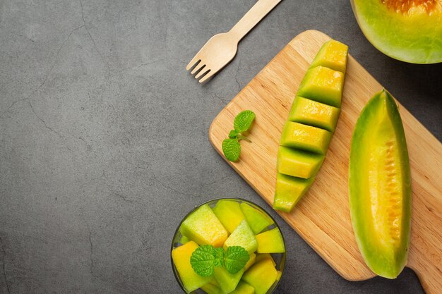 Melón fresco, cortado en trozos, colocado en una tabla de cortar de madera