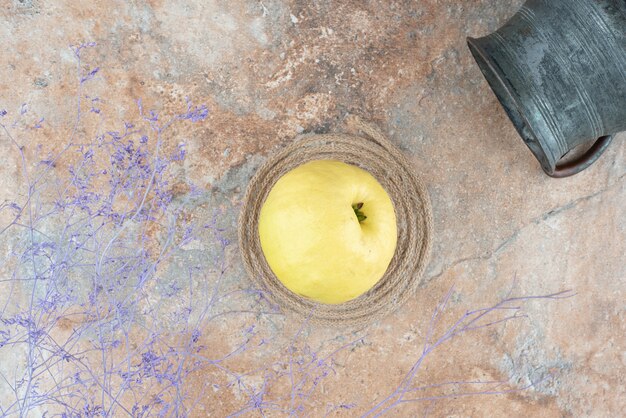 Un membrillo fresco con una copa antigua sobre una mesa de mármol.