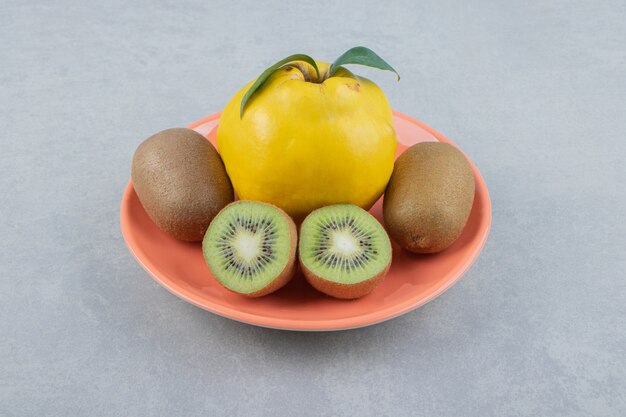 Membrillo y kiwis en rodajas sobre placa naranja