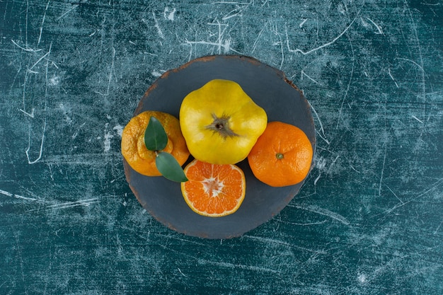 Membrillos y naranjas sobre una tabla, sobre el fondo de mármol. Foto de alta calidad