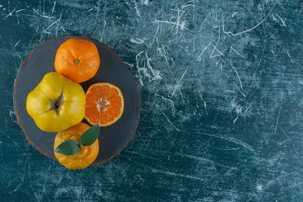 Membrillos y naranjas sobre una tabla, sobre la mesa de mármol.