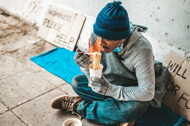 Foto gratuita los mendigos se sentaron envueltos en paños y comiendo fideos.