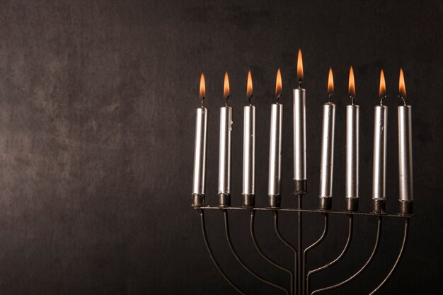 Menorah con velas cerca de la pared gris