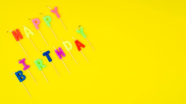 Mensaje de feliz cumpleaños con velas de colores y espacio de copia