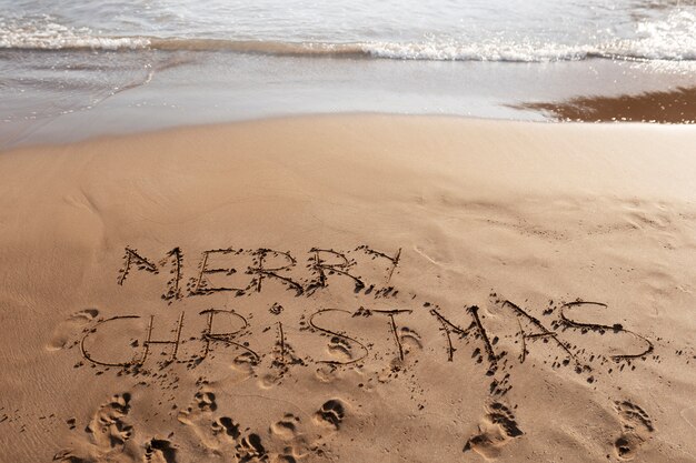 Mensaje de feliz navidad de alto ángulo en la arena