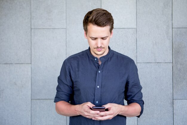 Mensaje de mensajes de texto de hombre joven serio en smartphone