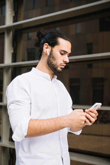 Mensaje de texto de empresario elegante en teléfono inteligente al aire libre