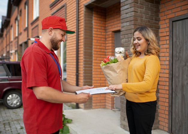 Foto gratuita mensajero entregando comestibles a casa