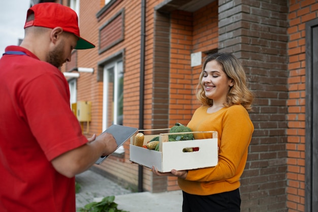 Foto gratuita mensajero entregando comestibles a casa