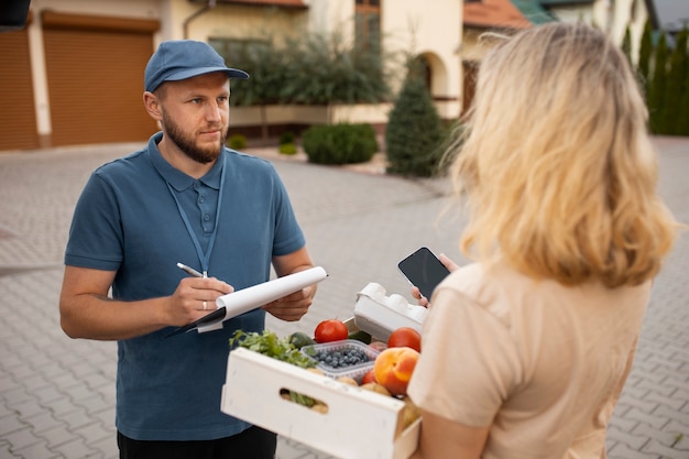 Foto gratuita mensajero entregando comestibles a casa