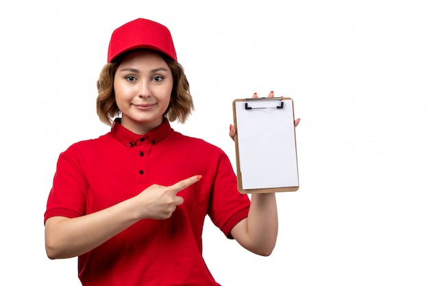 Foto gratuita un mensajero femenino joven de la vista frontal en camisa roja gorra roja sosteniendo el bloc de notas sonriendo