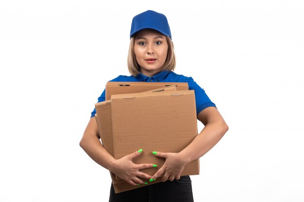 Un mensajero femenino joven de la vista frontal en uniforme azul que sostiene los paquetes de entrega de alimentos