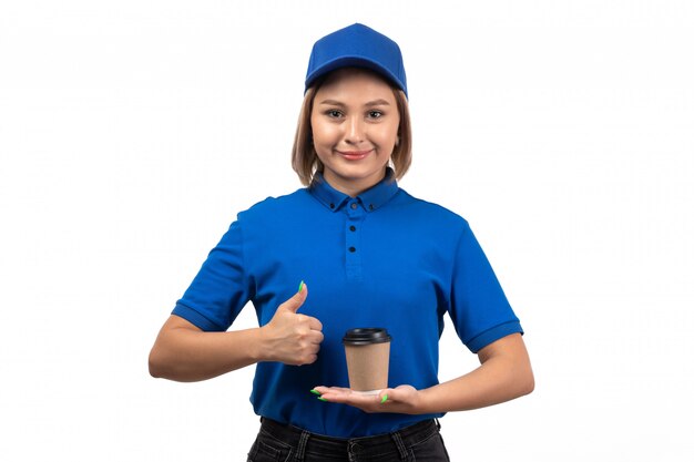 Un mensajero femenino joven de la vista frontal en uniforme azul que sostiene la taza de café