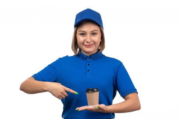 Un mensajero femenino joven de la vista frontal en uniforme azul que sostiene la taza de café