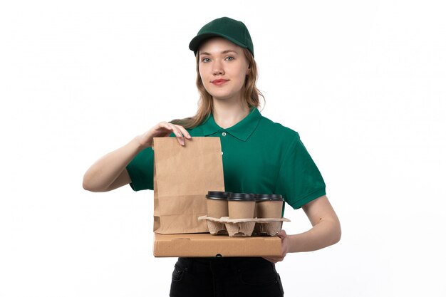 Un mensajero femenino joven de la vista frontal en uniforme verde que sostiene las tazas de café y los paquetes de comida