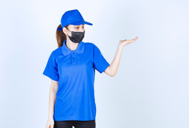 Mensajero femenino en máscara y uniforme azul y mostrando algo en el lado derecho