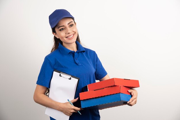 Mensajero femenino positivo con cartón de pizza y portapapeles