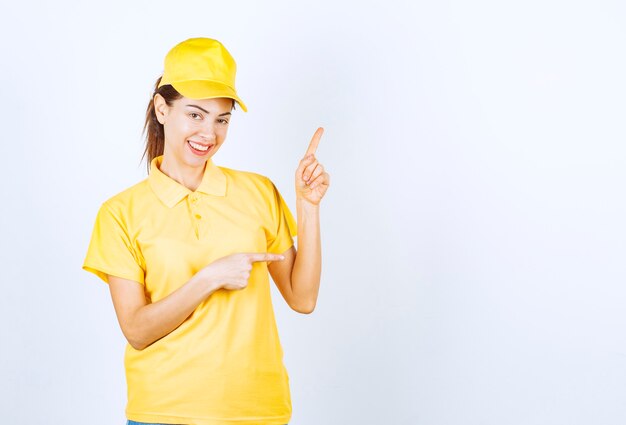 Mensajero femenino en uniforme amarillo que muestra algo arriba.