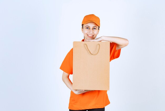 Mensajero femenino en uniforme naranja entregando una bolsa de compras