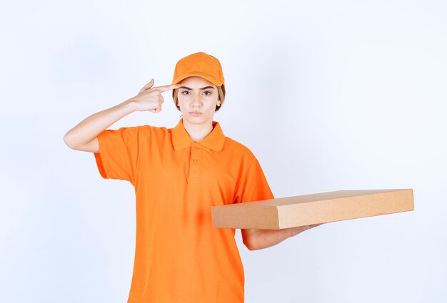 Mensajero femenino en uniforme naranja entregando una caja de cartón y parece confundido y vacilante