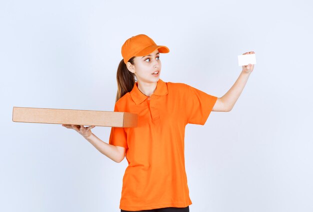 Mensajero femenino en uniforme naranja sosteniendo una caja de pizza para llevar y presentando su tarjeta de visita