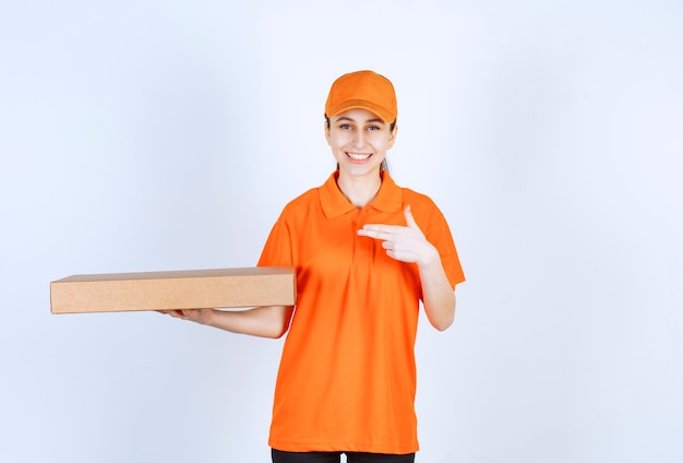 Mensajero femenino en uniforme naranja sosteniendo una caja de pizza para llevar