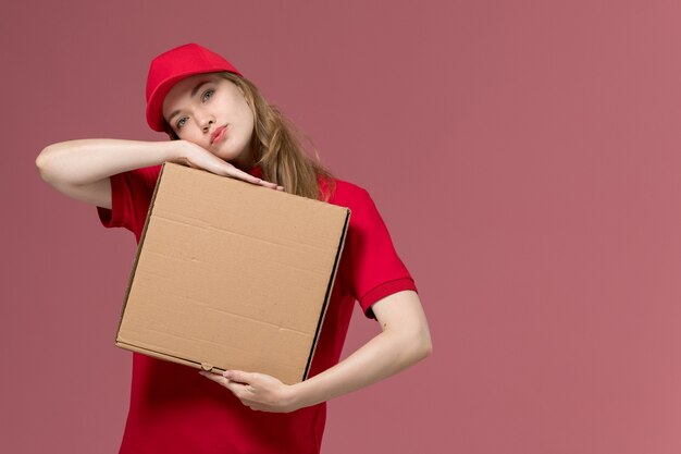 Mensajero femenino en uniforme rojo con caja de comida de entrega en rosa claro, servicio de trabajo uniforme chica de entrega del trabajador