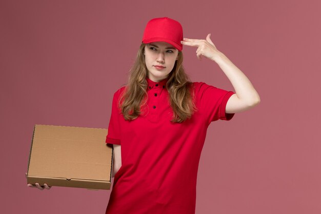 Mensajero femenino en uniforme rojo con caja de entrega de alimentos pensando en rosa, trabajador de trabajo de entrega de servicio uniforme