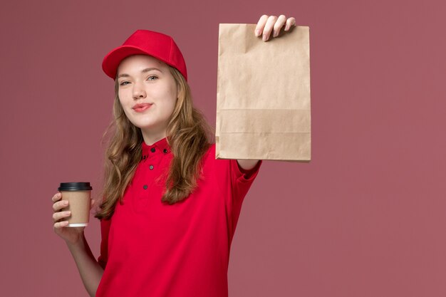 Mensajero femenino en uniforme rojo con paquete de comida y café en rosa, trabajo de trabajador de entrega de servicio uniforme