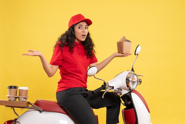 Mensajero femenino de vista frontal en bicicleta para entrega de café y comida sobre fondo amarillo trabajo de servicio trabajador de entrega mujer de trabajo